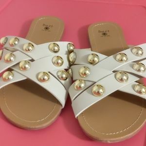 White slip on sandals decorated with gold beads.